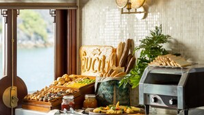 A buffet with various food items, a grill, and a view of the outdoors. - The Au Co Cruise - Longest Cruise 2 Bays (Tuan Chau)