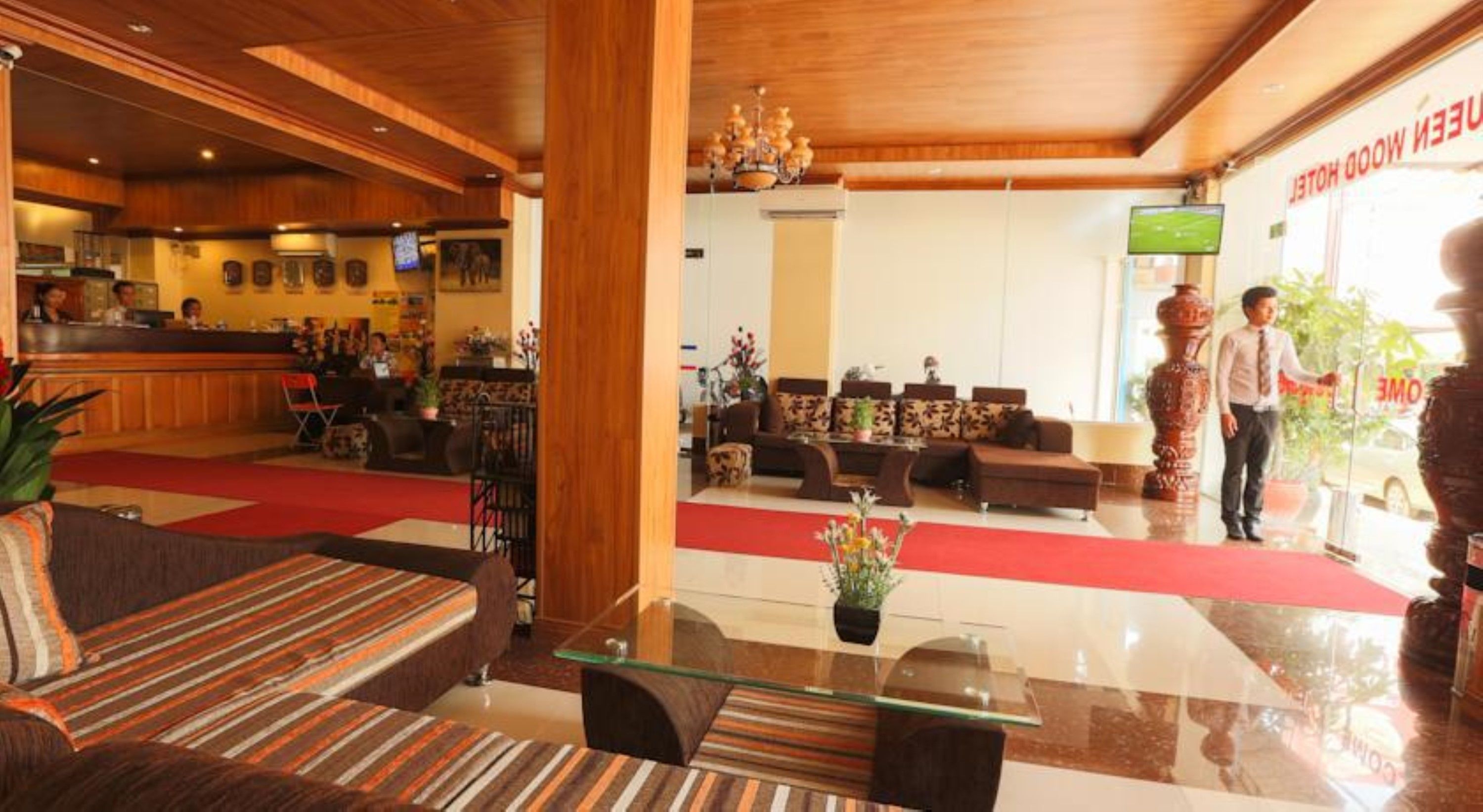 Vestíbulo de hotel con mostrador de recepción, zona de estar y una columna de madera grande.