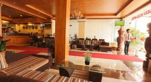 A hotel lobby with a reception desk, seating area, and a large wooden column. - Queen Wood Hotel (Phnom Penh)