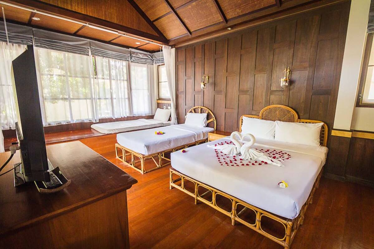 A hotel room with two single beds, a television, and a wooden floor.