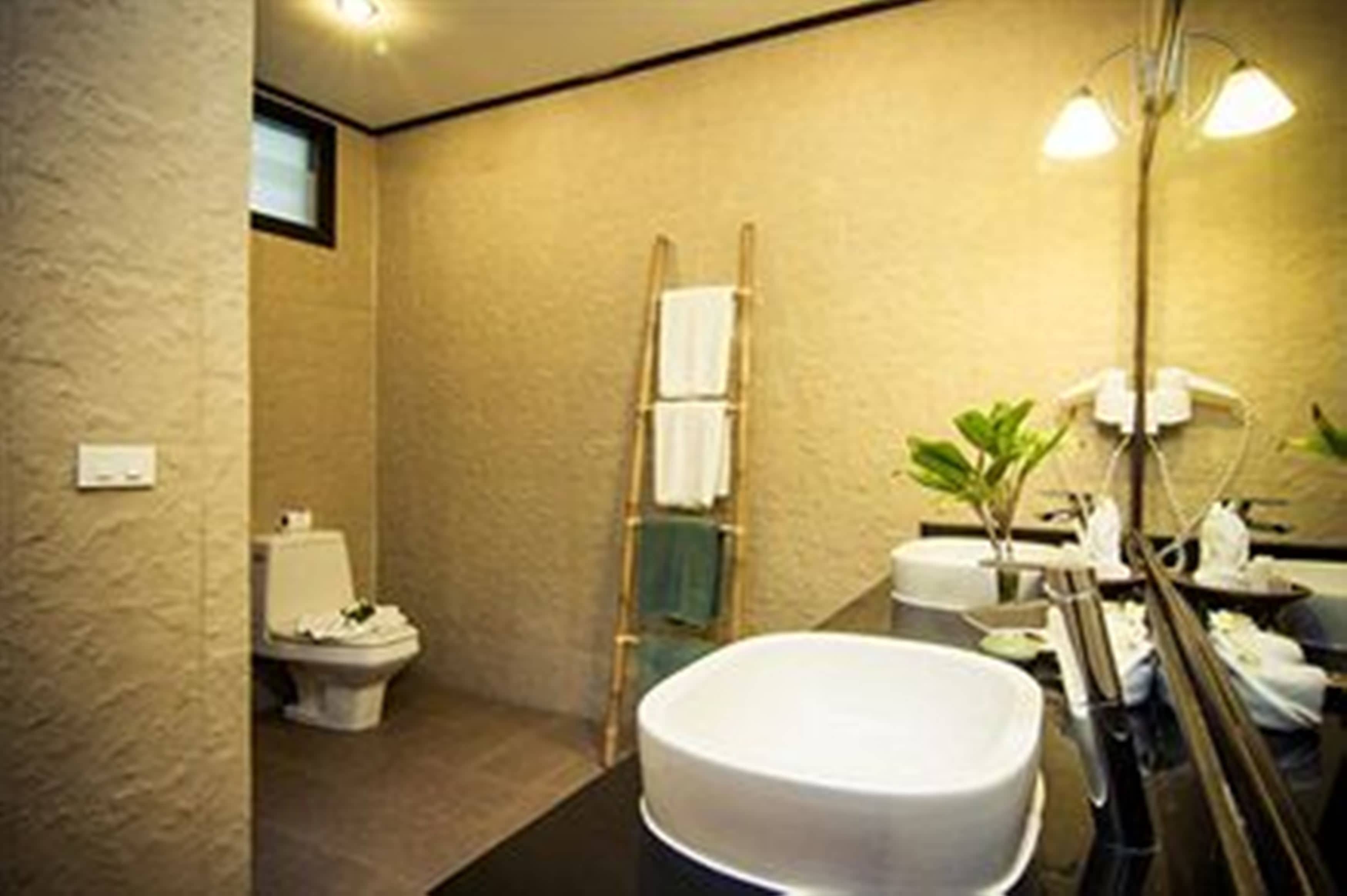 A bathroom with a toilet, a sink, a mirror, and a towel rack.
