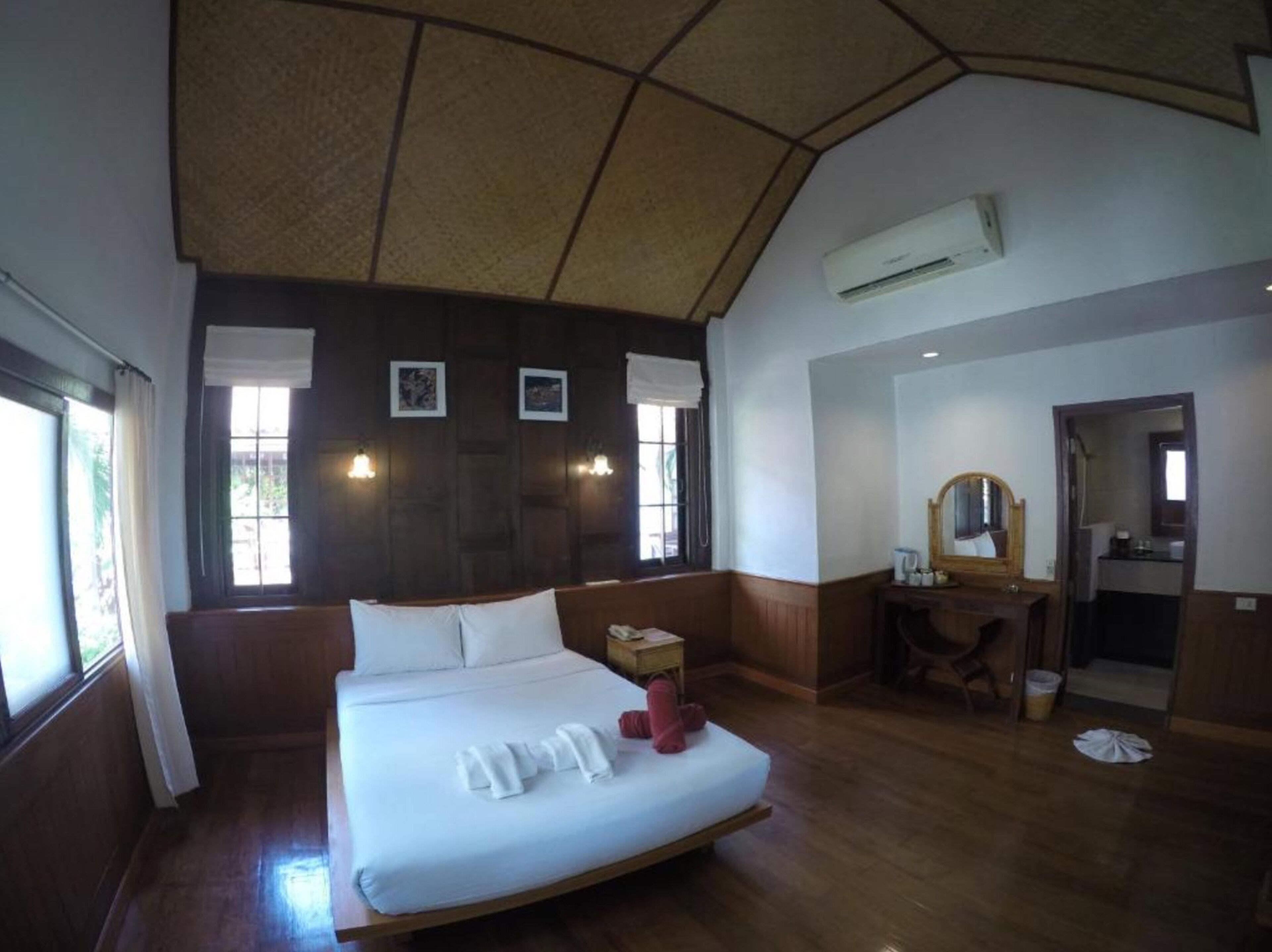 A hotel room with a large bed, a desk, a mirror, and a bathroom visible through an open door.