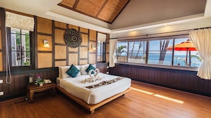 A spacious bedroom with a large bed, wooden flooring, a view of the ocean, and a ceiling with exposed beams. - Coco Palm Beach Resort (Koh Samui)