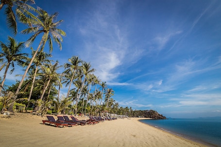 On the beach, white sand, beach umbrellas, beach towels. Coco Palm Beach Resort
