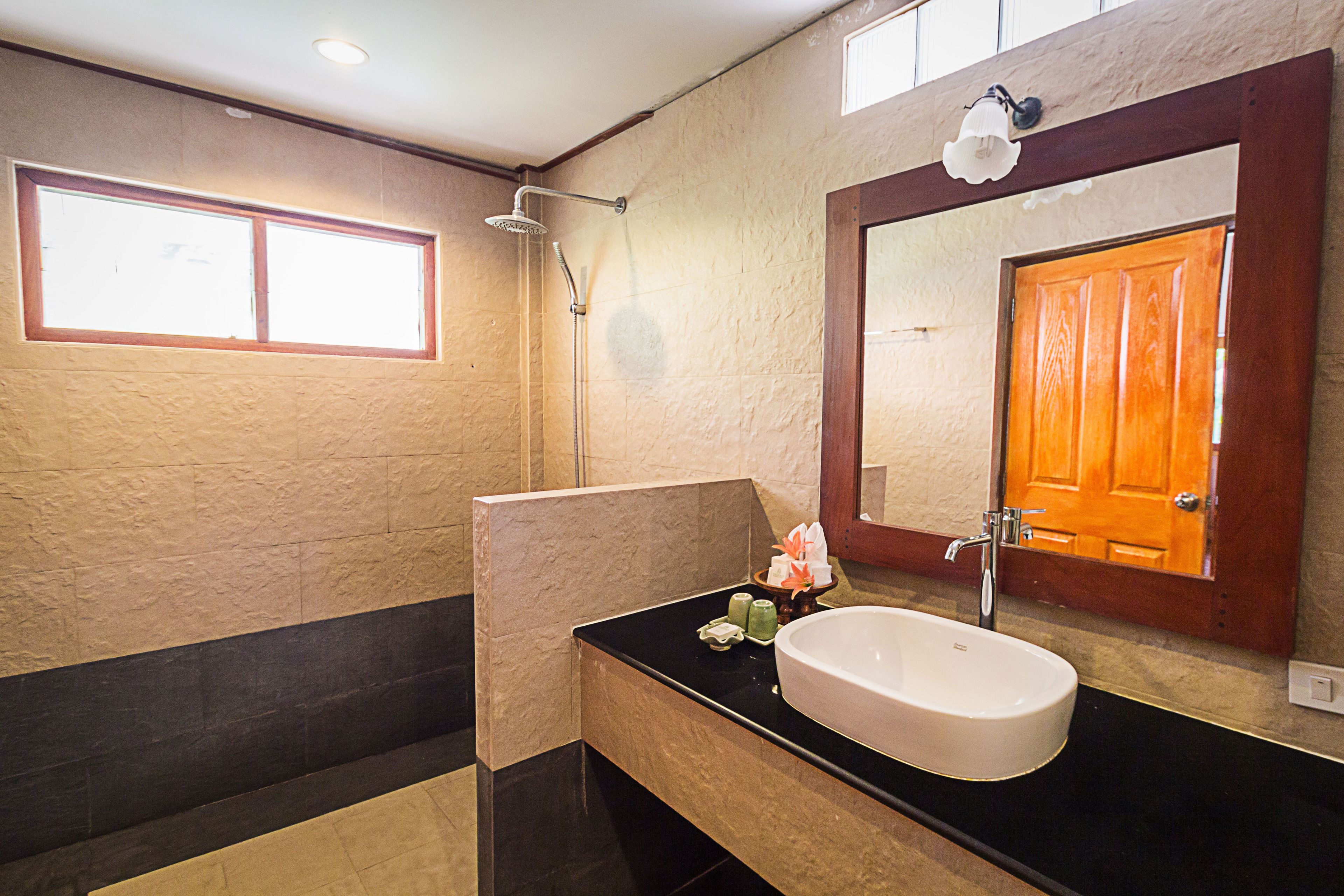 A bathroom with a large mirror, a sink, and a shower.