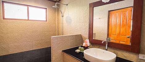 A bathroom with a large mirror, a sink, and a shower.