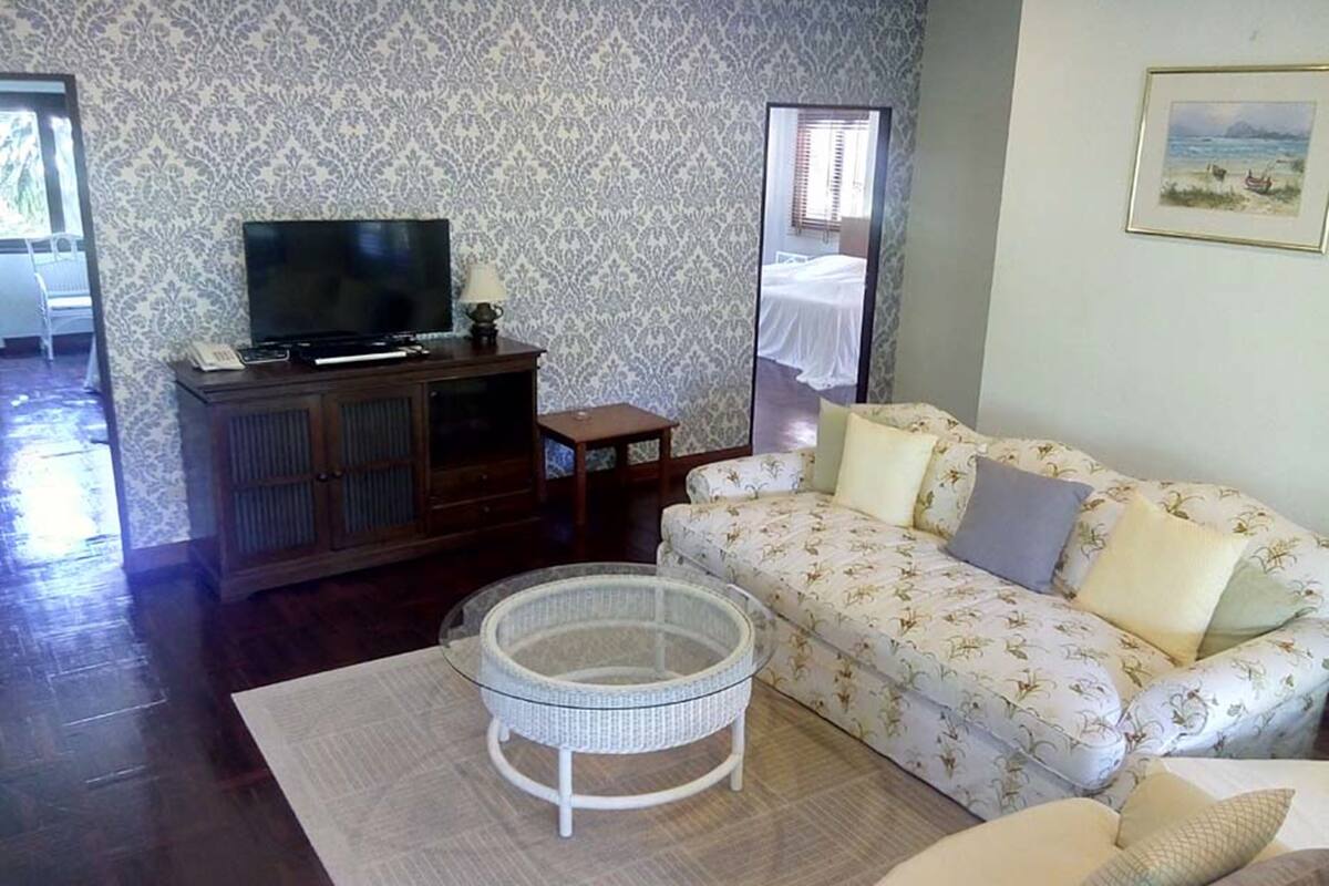 A living room with a sofa, a television, a small table, and a mirror.