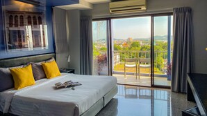 A modern hotel room with a large bed, a balcony with a view, and an air conditioning unit. - Sino Inn (Phuket)