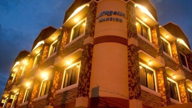 Un hôtel à la façade incurvée, doté de nombreux balcons et d’une colonne centrale sur laquelle est inscrit le nom « Vanguard Mansion ».