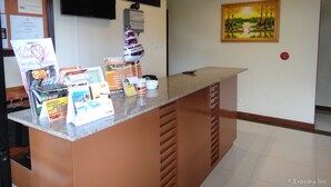 Un comptoir d’accueil avec des brochures d’information, une horloge et un tableau accroché au mur.