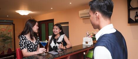 A bar area with a marble countertop, a bottle of wine, and a woman holding a glass.