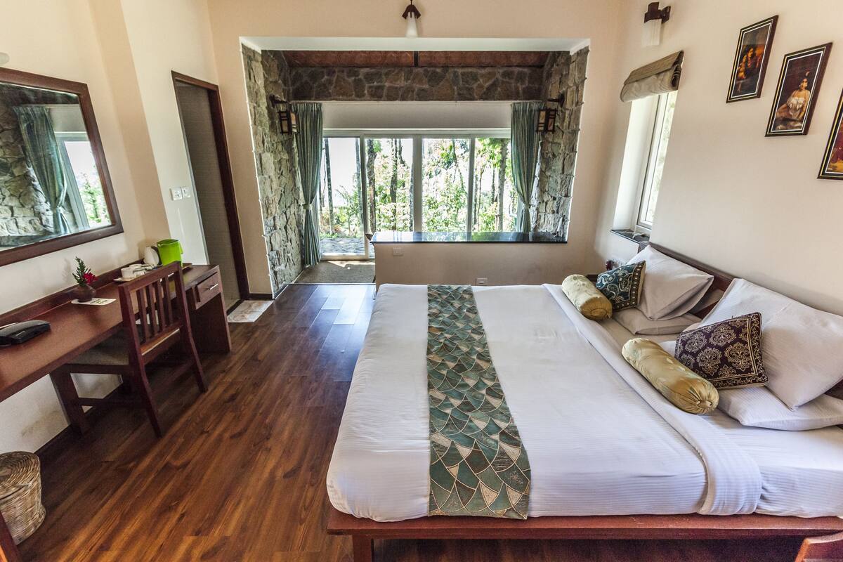 Un dormitorio con cama, escritorio y vista al exterior.