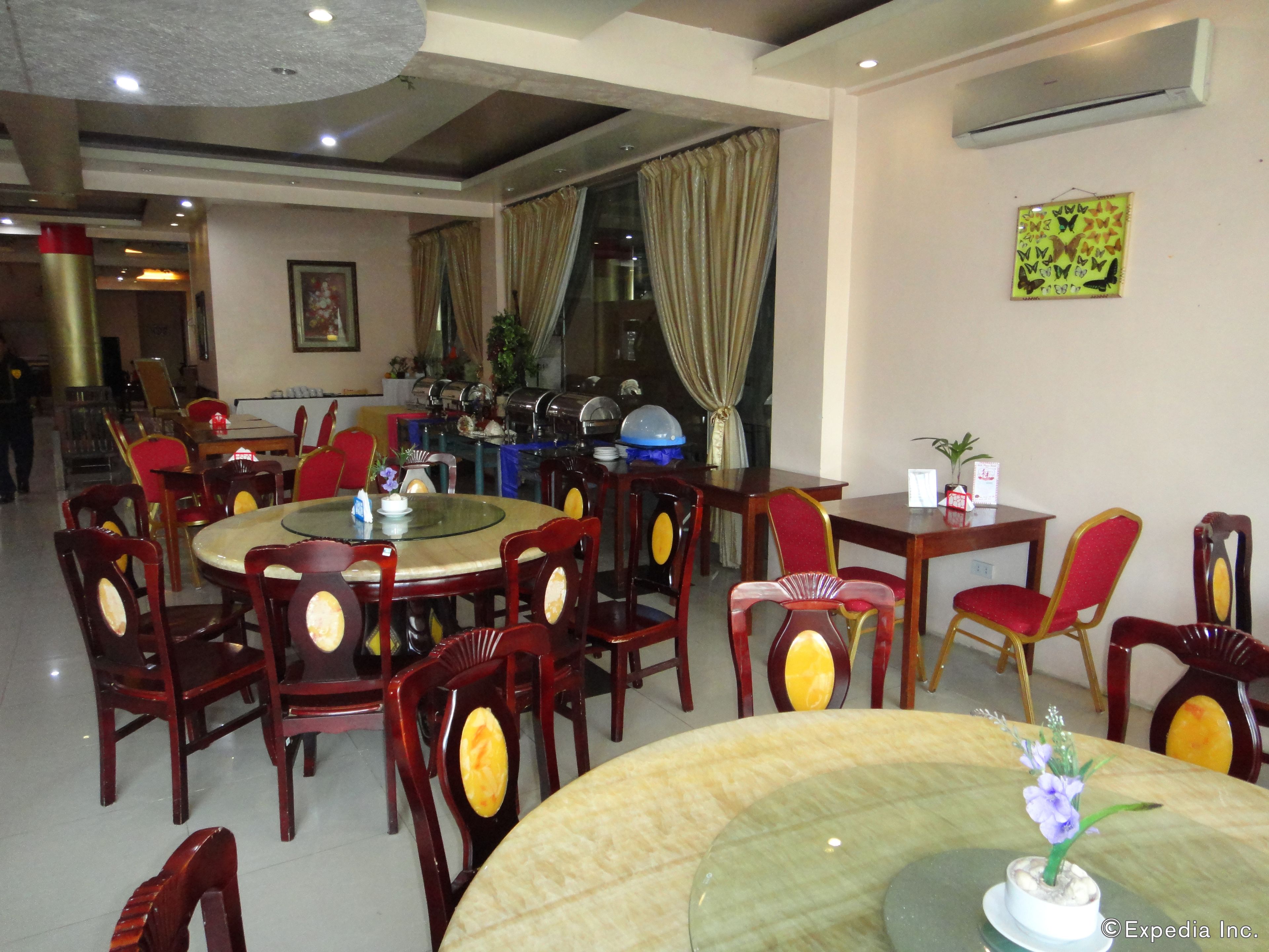 A dining area with round tables and chairs, buffet setup, and an air conditioning unit on the wall.