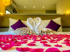 A bed with a heart-shaped towel arrangement and rose petals on the bedspread. - Sino Imperial Design Hotel (Phuket)