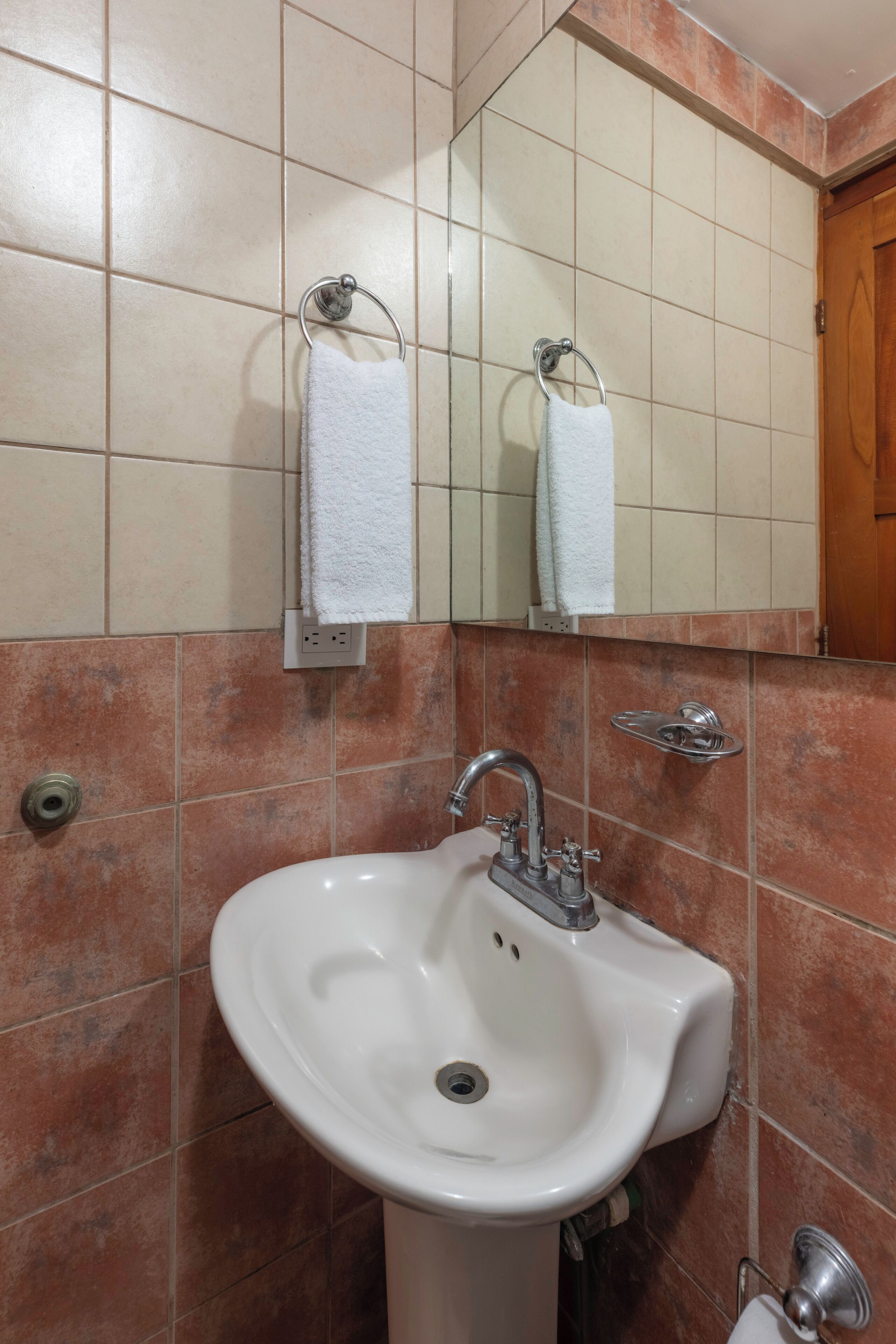 A bathroom with a white sink, a mirror, and two towel racks.