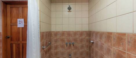 A shower area with tiled walls, a wooden door, and a showerhead.