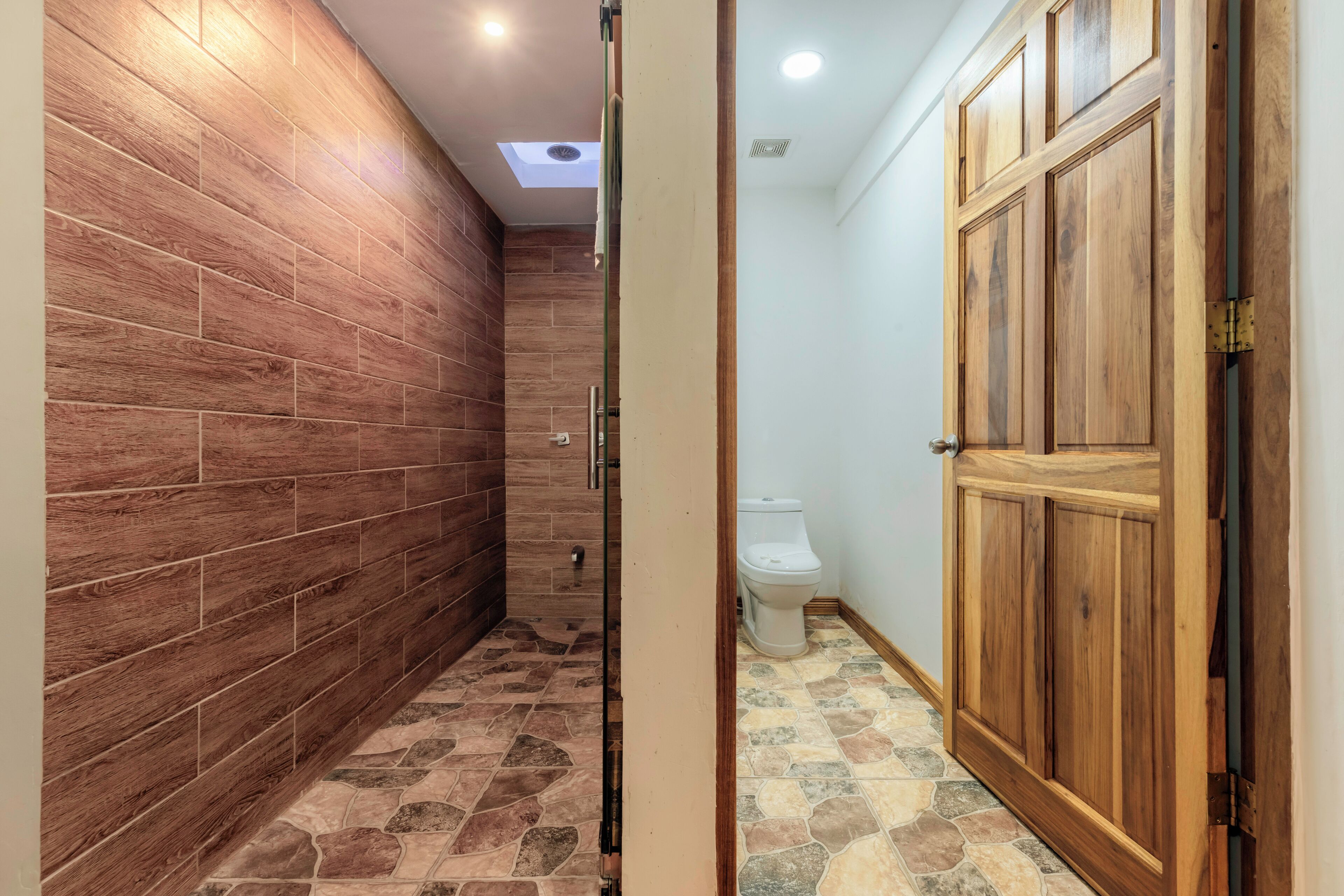 A bathroom with wooden walls, a shower area, and a toilet.