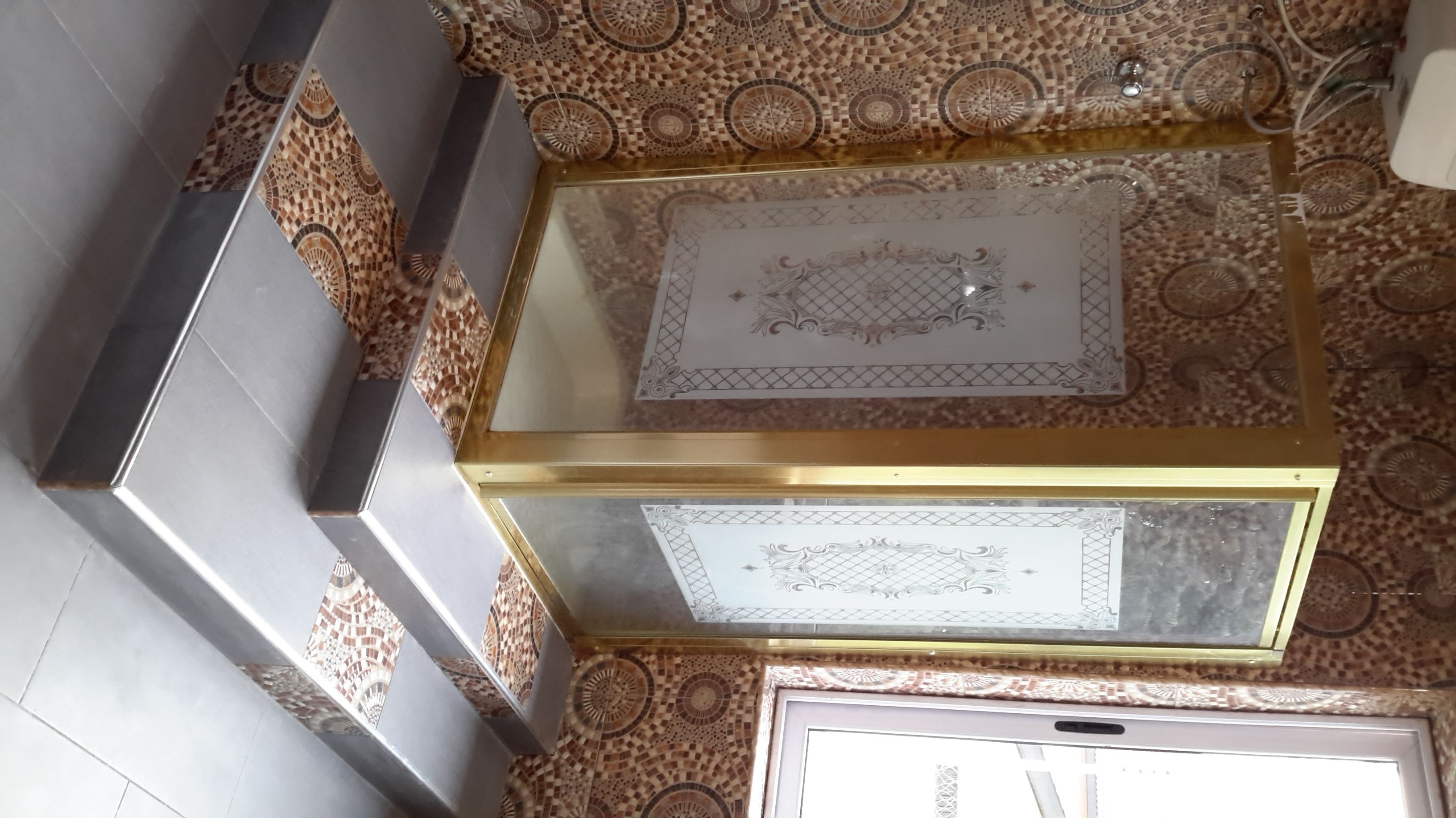 Um quarto com piso estampado, uma vitrine de vidro com objetos decorativos e uma obra de arte emoldurada na parede.