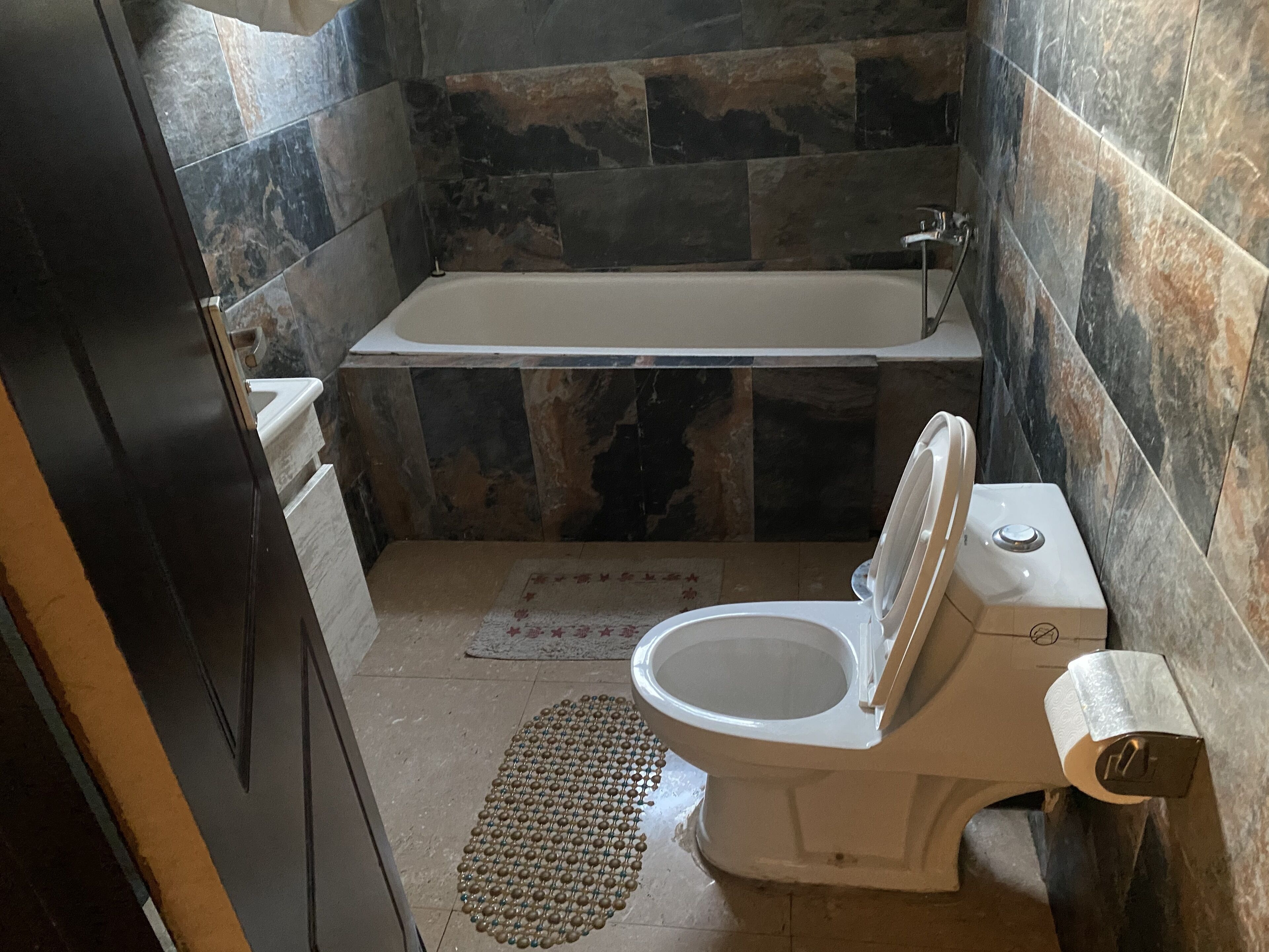A bathroom with a bathtub, toilet, and a shower area.
