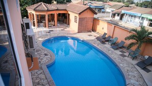 A swimming pool with lounge chairs and a covered seating area. - Tribeca Hotel (Accra)