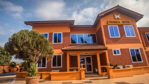 A two-story hotel with a red and orange facade, a tiled entrance, and a sign reading "Tribeca Hotel". - Tribeca Hotel (Accra)