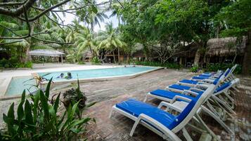 Una piscina al aire libre, sillones reclinables de piscina