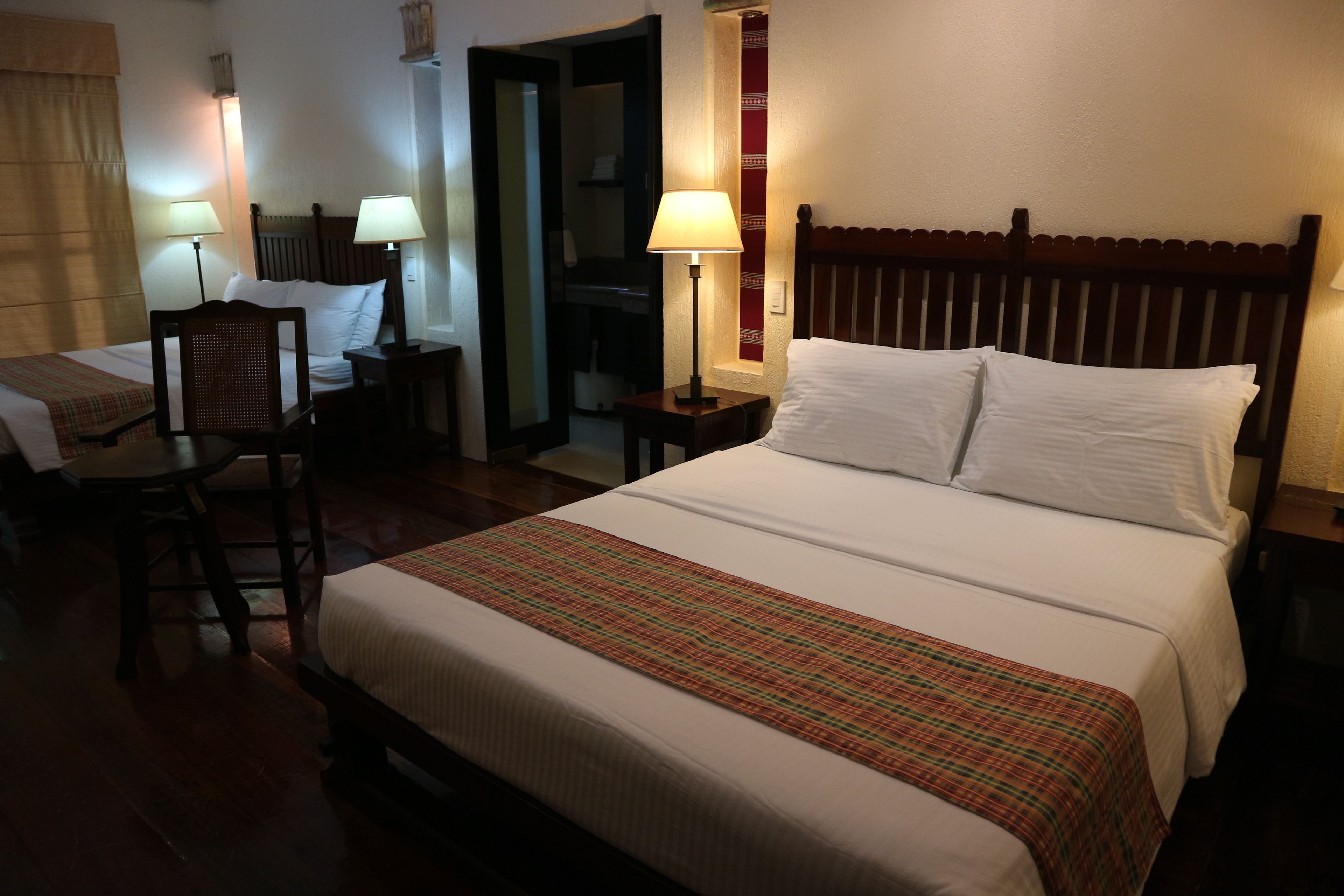 A hotel room with a large bed, two bedside tables with lamps, a chair, and a small desk.