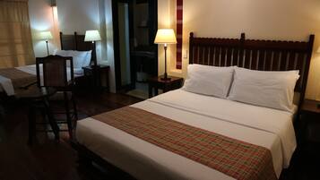 A hotel room with a large bed, two bedside tables with lamps, a chair, and a small desk.