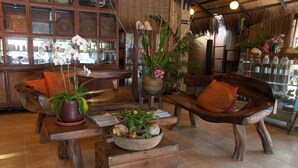 A rustic interior with wooden furniture, a central table with a bowl of fruits and flowers, and a bookshelf filled with books and decorative items. - Sea Wind Resort (Boracay Island)