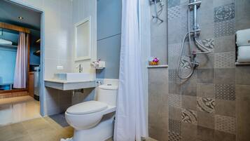 A bathroom with a toilet, sink, shower, and a towel rack.