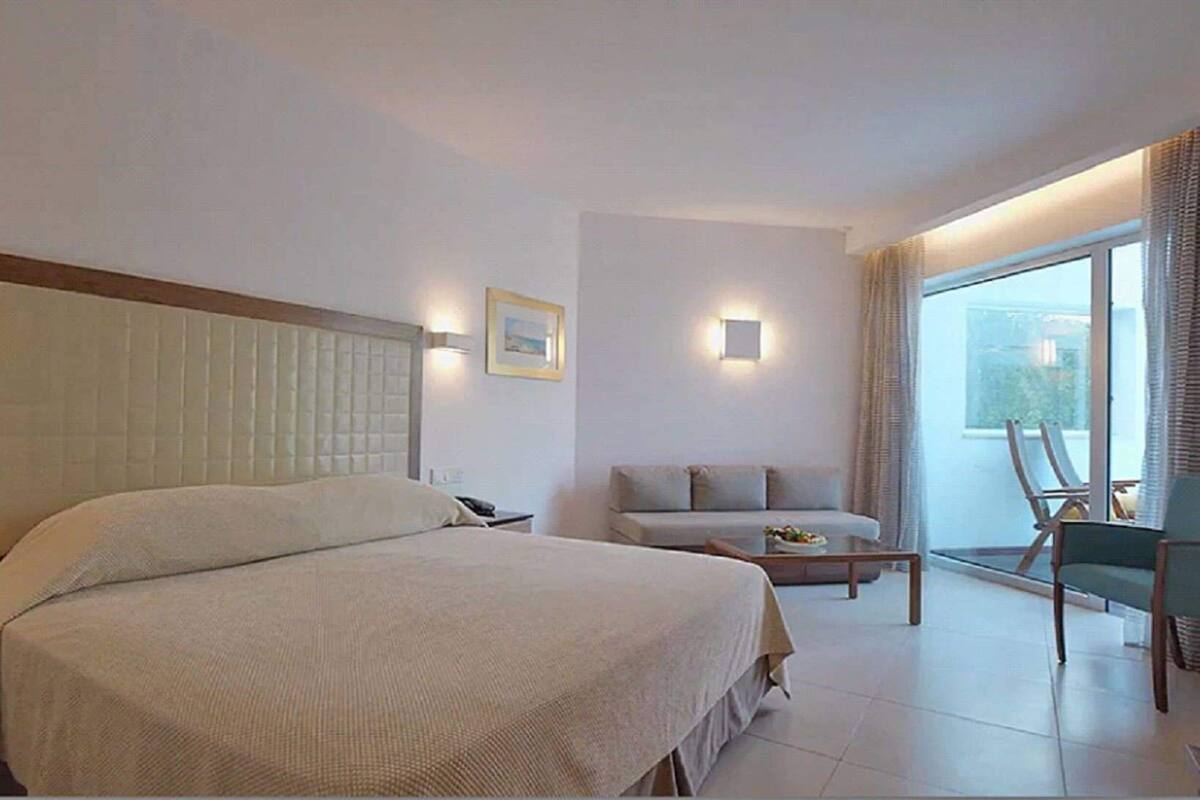 Une chambre d’hôtel avec un grand lit, un canapé, une petite table et une chaise.