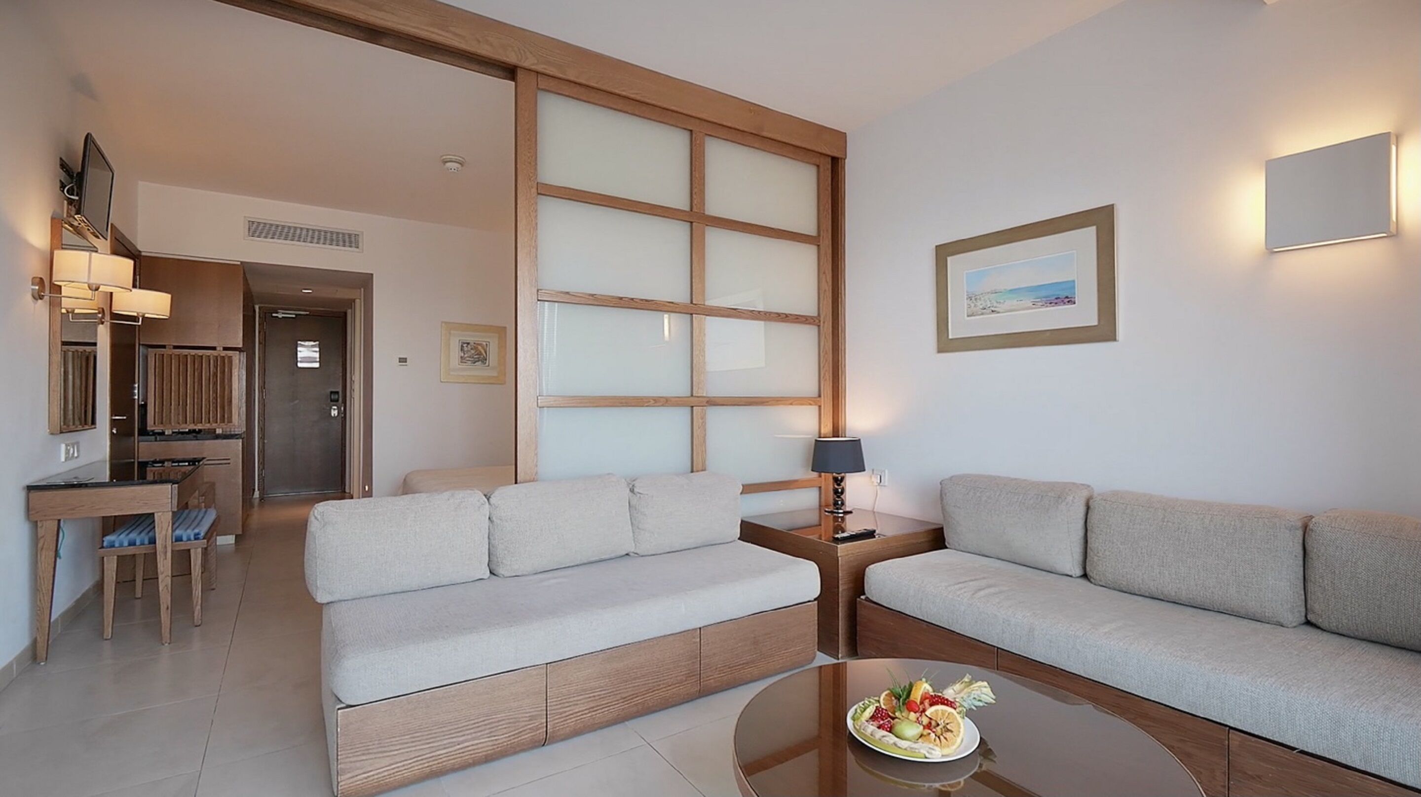 A modern living room with a sofa, a dining table, and a kitchen area.