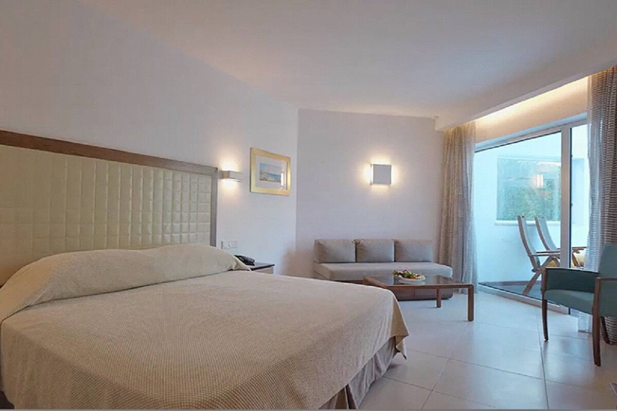 Une chambre d’hôtel avec un grand lit, un canapé, une table basse et une vue sur l’extérieur.