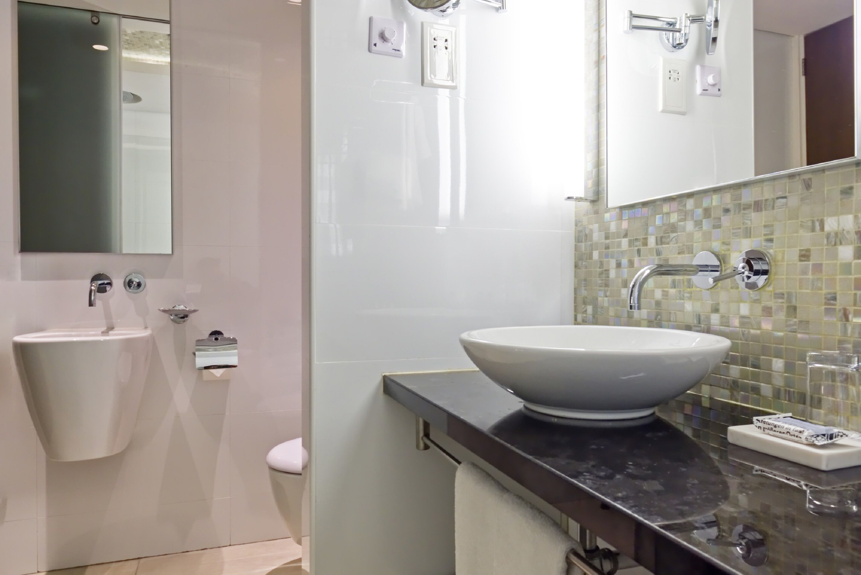 Un baño moderno con un espejo grande, dos lavamanos, un inodoro y un salpicadero de azulejos.