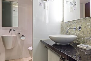 Casa de banho moderna com um espelho grande, duas pias, uma sanita e um painel de azulejos.