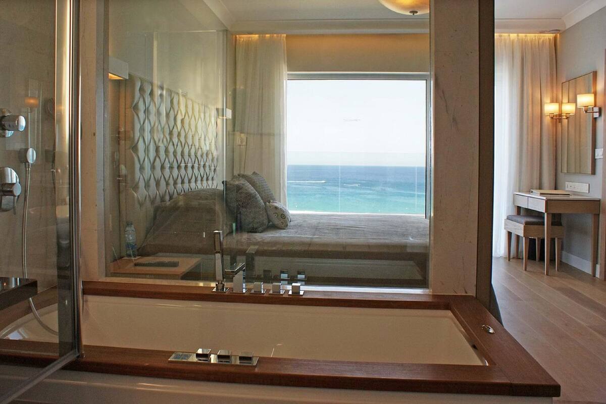 Une salle de bain moderne dotée d’une grande baignoire, d’une douche à parois de verre et offrant une vue sur l’océan.