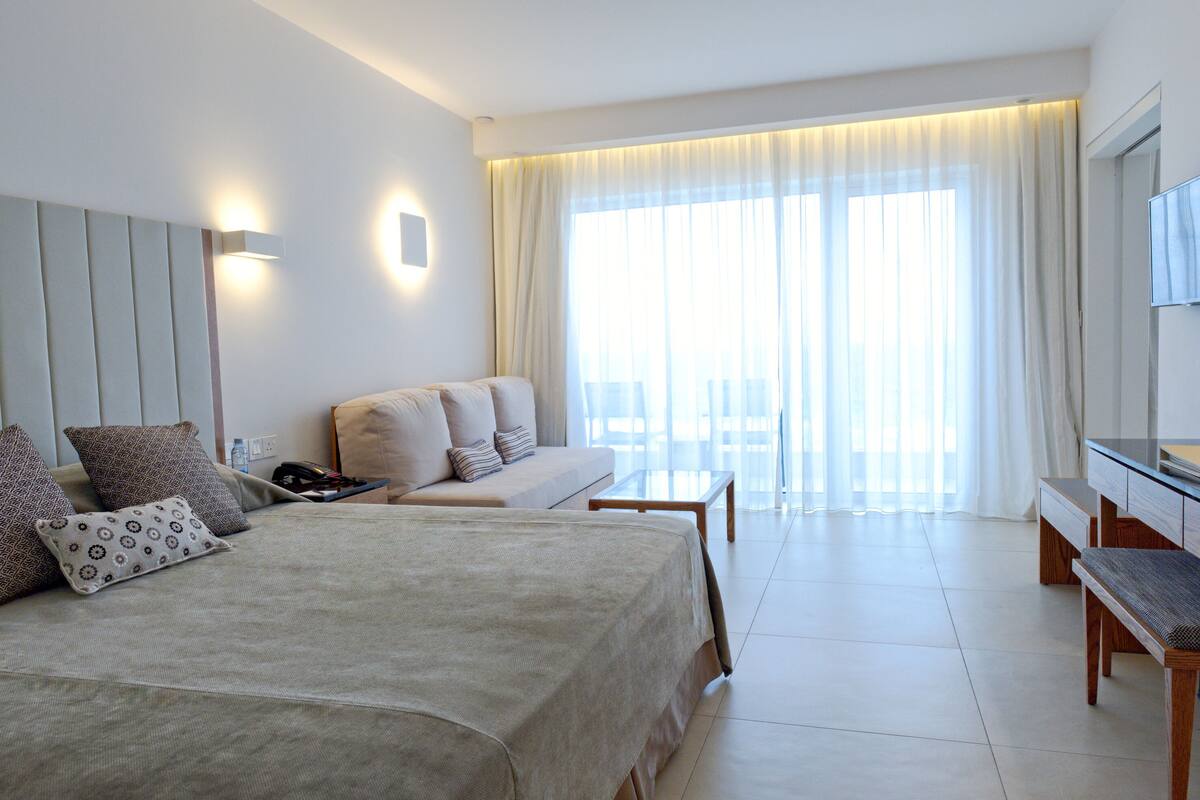 Une chambre d’hôtel moderne avec un grand lit, un canapé, un bureau et une télévision.