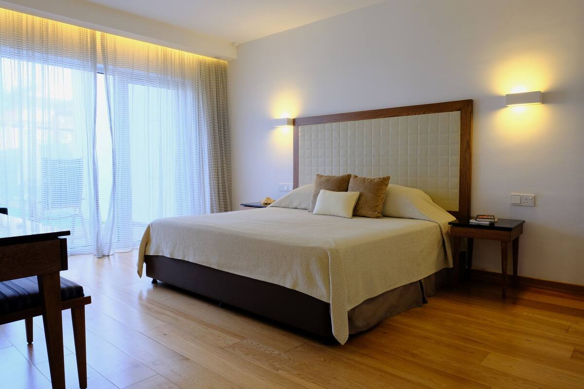 Une chambre à coucher bien rangée, avec un grand lit, des tables de chevet et une chaise.