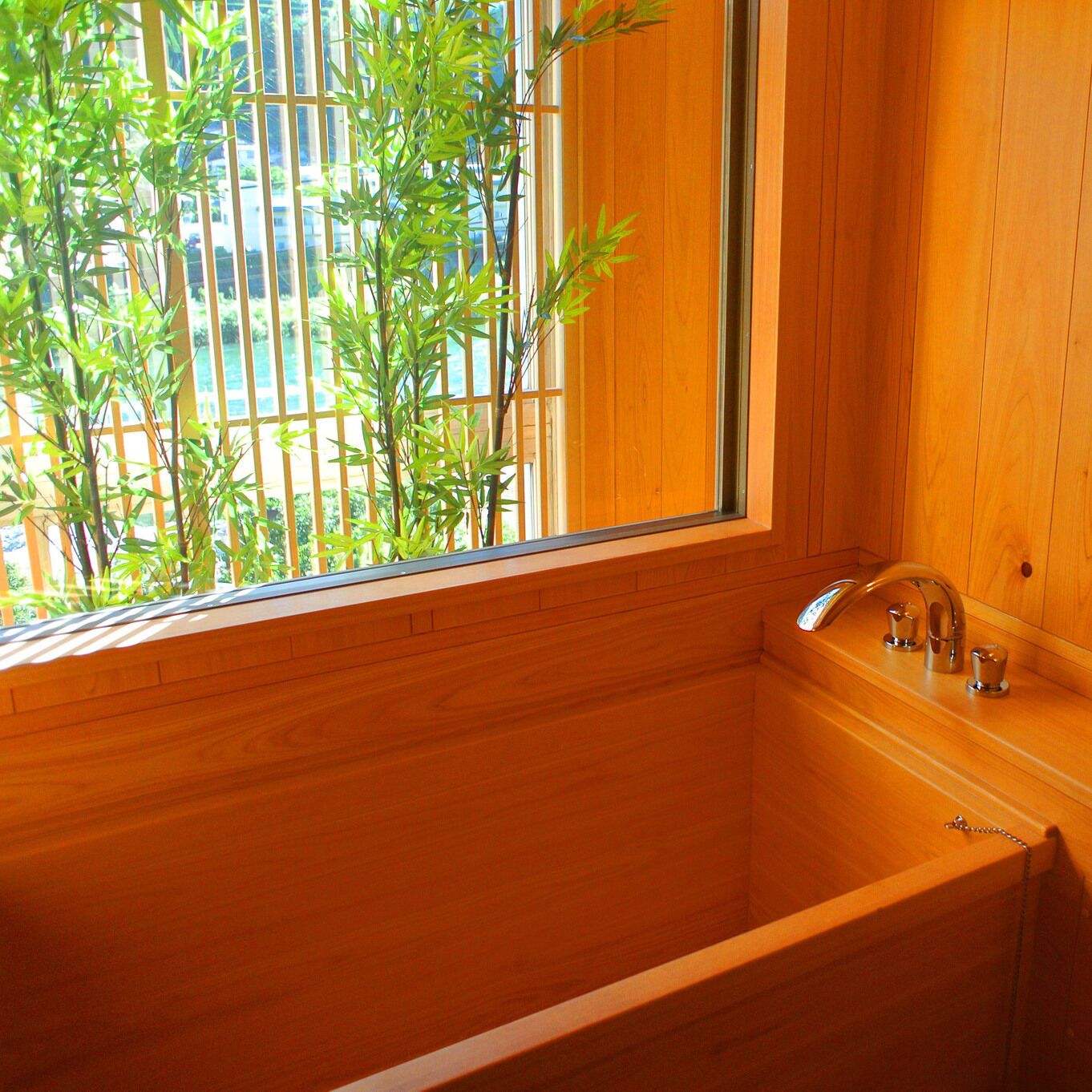 Una bañera de madera con ventanal, un grifo y un pequeño estante con objetos.