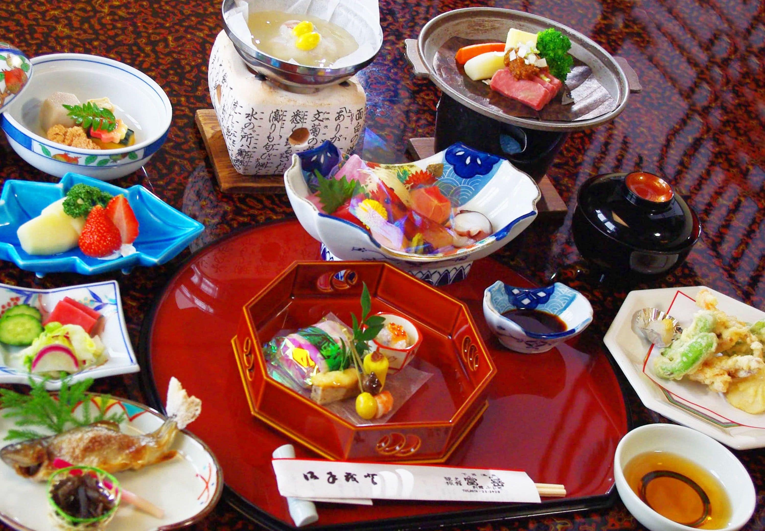 A variety of dishes on a table, including sushi, sashimi, and other Japanese cuisine.