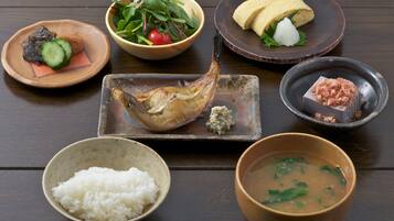 Une variété de plats, notamment du poisson, du riz et de la soupe, disposés sur une table en bois.