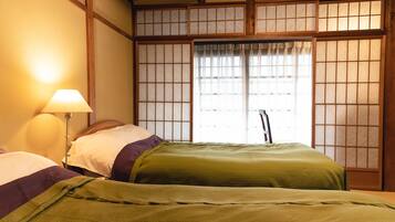 Habitació tradicional japonesa amb tatami, un panell shoji i un llit amb roba de llit verda.