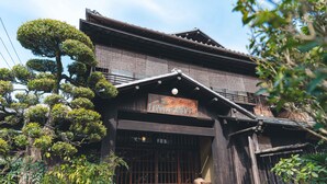 Un edificio tradicional japonés con fachada de madera, grandes puertas correderas y un letrero.