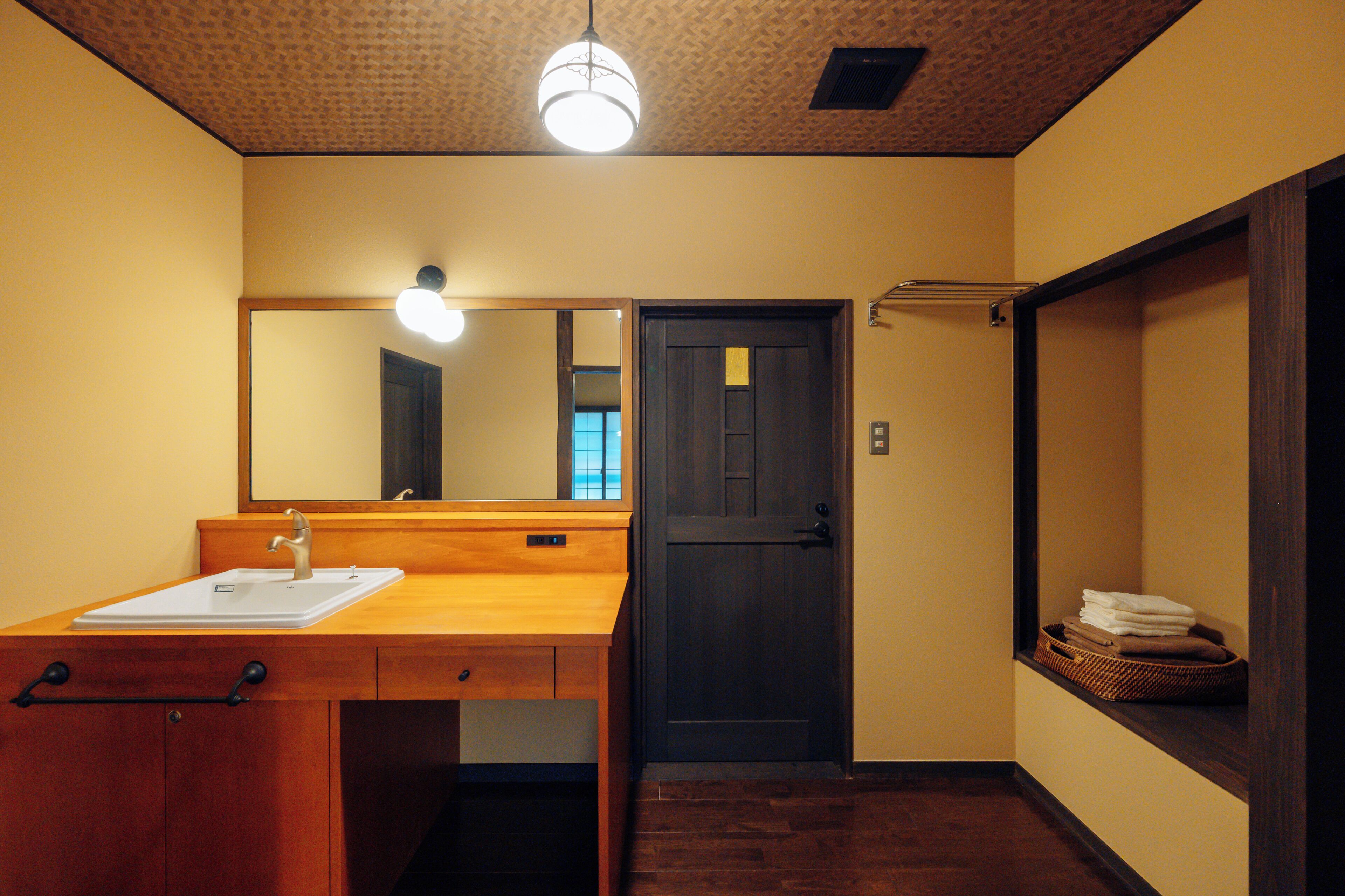 A bathroom with a wooden vanity, a mirror, a sink, and a door.