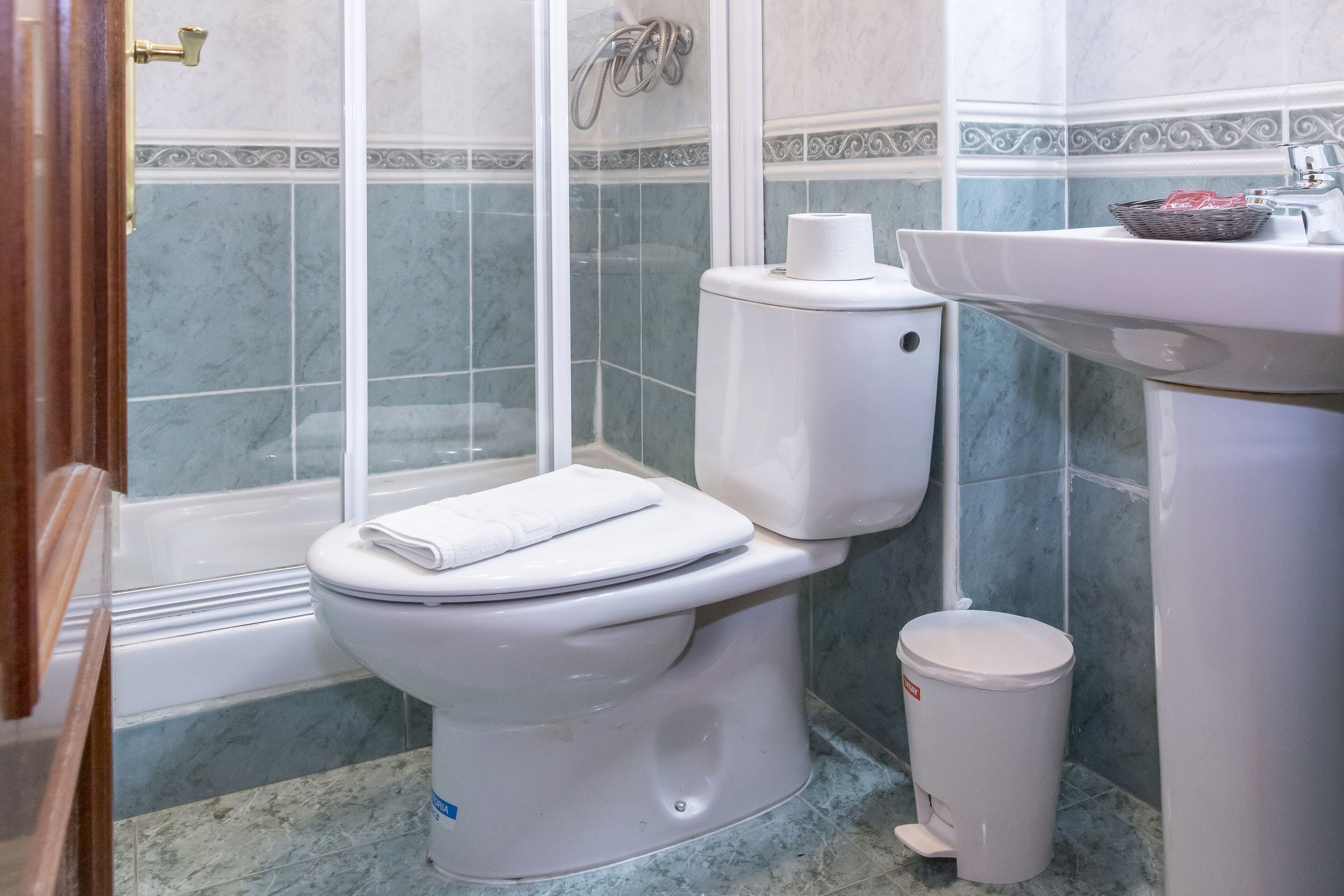 Un baño con inodoro, bidé, lavamanos y cubo de basura.