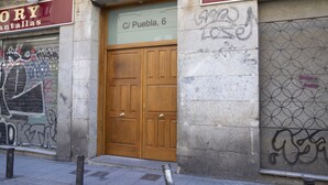 Eine geschlossene Holztür mit einem Schild darüber, auf dem 'C/ Puebla, 6' steht.