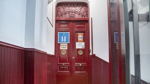 Eine rote Doppeltür mit einem blauen Schild, das ein Hostel anzeigt.