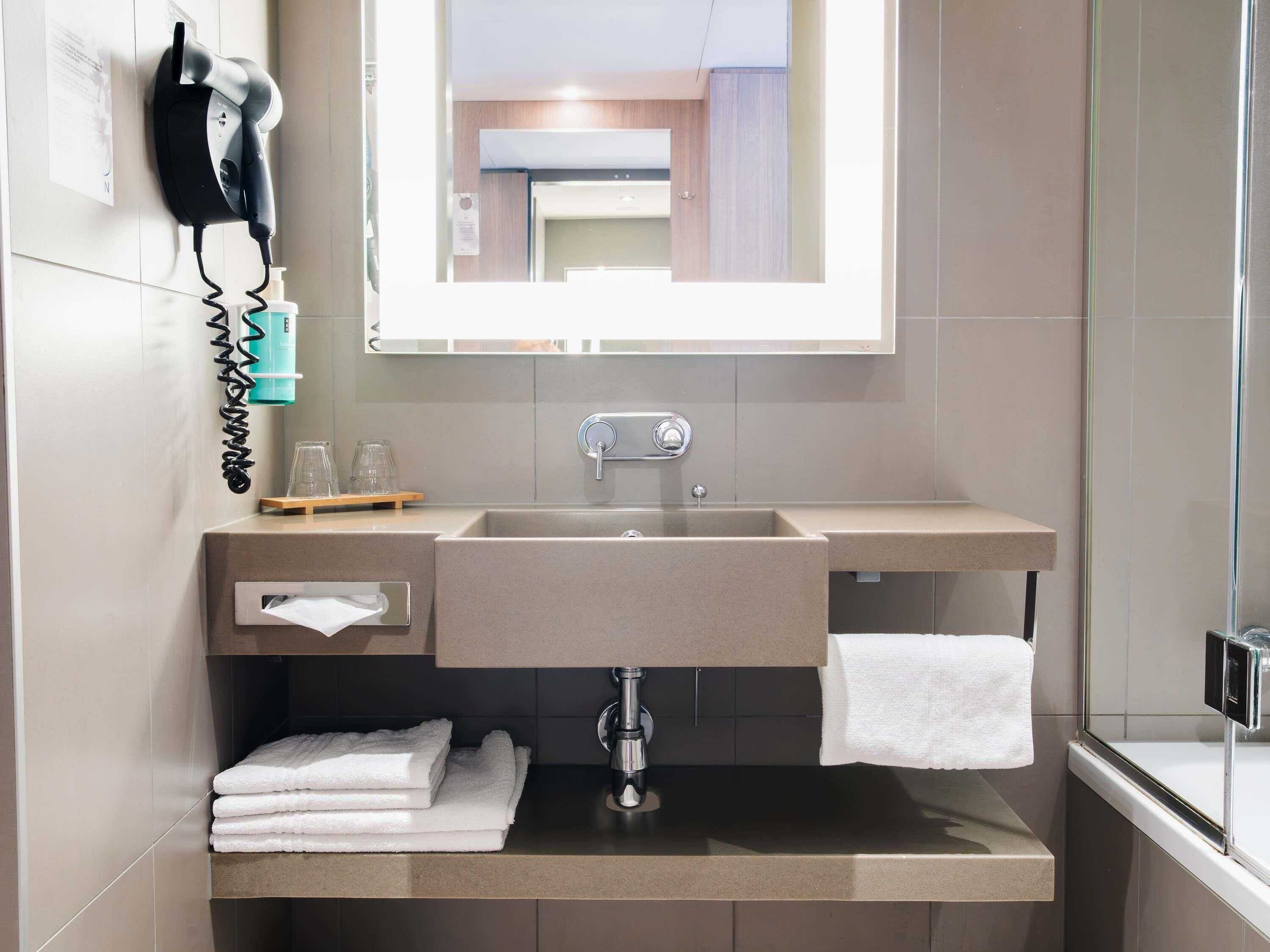 A bathroom with a sink, mirror, towel rack, and hairdryer.