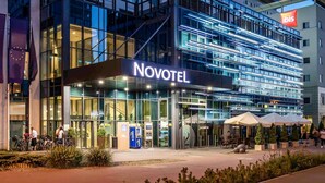 A modern hotel with a glass facade, labeled "NOVOTEL," featuring a prominent entrance and outdoor seating area. - Novotel Lodz Centrum (Lodz)