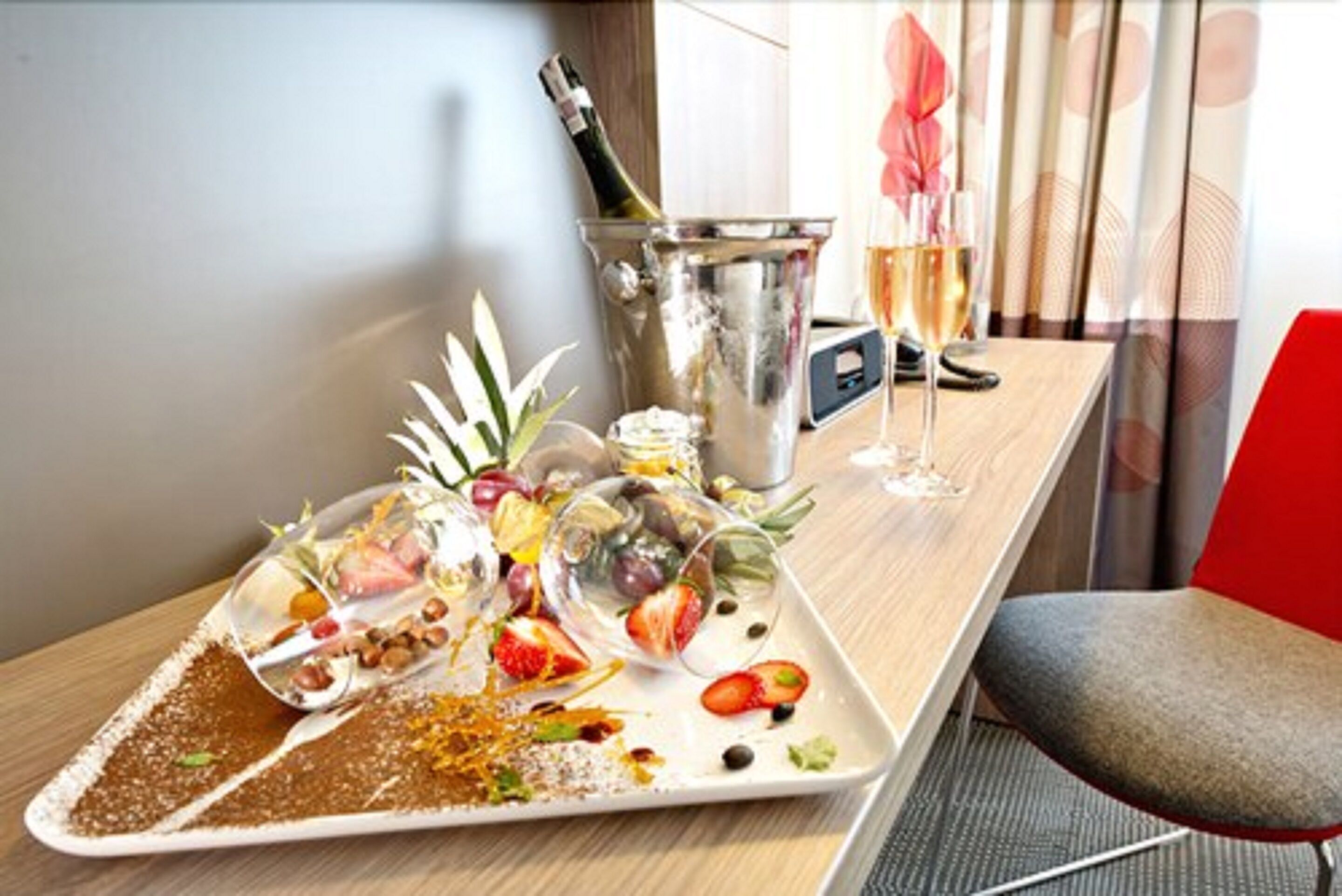Een dienblad met verschillende soorten eten, een champagnefles en een wijnglas op een hoteltafel.